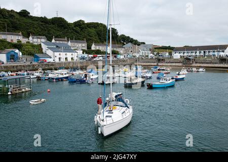 Eine Yacht, die den Hafen von Porthleven, Cornwall verlässt Stockfoto
