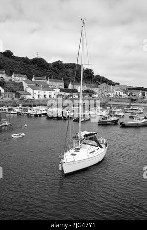 Eine Yacht, die den Hafen von Porthleven, Cornwall verlässt Stockfoto
