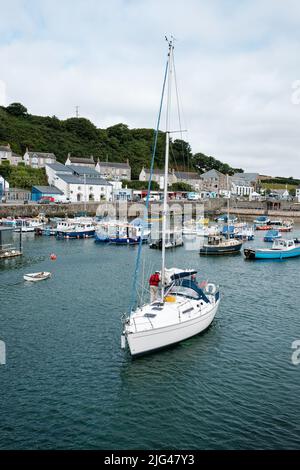 Eine Yacht, die den Hafen von Porthleven, Cornwall verlässt Stockfoto