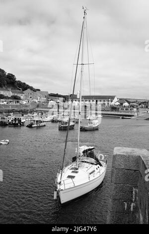 Eine Yacht, die den Hafen von Porthleven, Cornwall verlässt Stockfoto