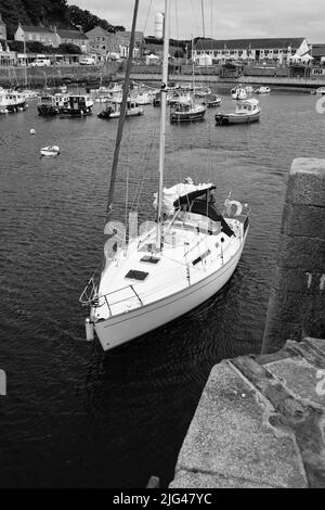 Eine Yacht, die den Hafen von Porthleven, Cornwall verlässt Stockfoto