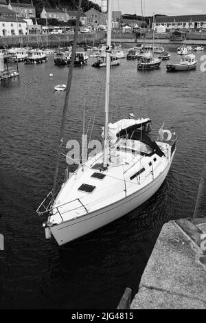 Eine Yacht, die den Hafen von Porthleven, Cornwall verlässt Stockfoto