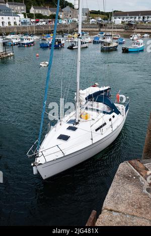 Eine Yacht, die den Hafen von Porthleven, Cornwall verlässt Stockfoto