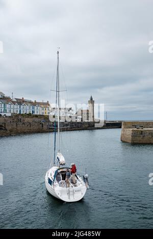 Eine Yacht, die den Hafen von Porthleven, Cornwall verlässt Stockfoto