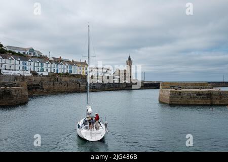 Eine Yacht, die den Hafen von Porthleven, Cornwall verlässt Stockfoto