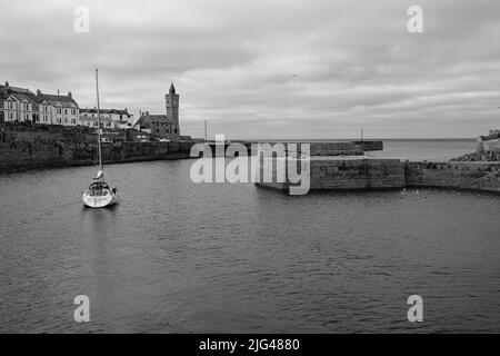 Eine Yacht, die den Hafen von Porthleven, Cornwall verlässt Stockfoto