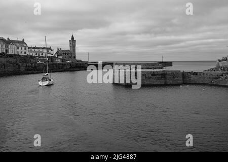 Eine Yacht, die den Hafen von Porthleven, Cornwall verlässt Stockfoto