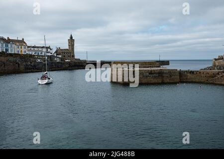 Eine Yacht, die den Hafen von Porthleven, Cornwall verlässt Stockfoto