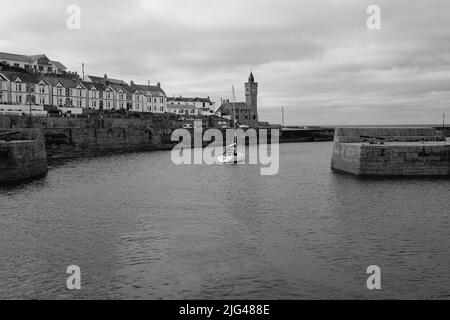 Eine Yacht, die den Hafen von Porthleven, Cornwall verlässt Stockfoto