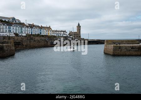 Eine Yacht, die den Hafen von Porthleven, Cornwall verlässt Stockfoto