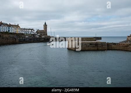 Eine Yacht, die den Hafen von Porthleven, Cornwall verlässt Stockfoto