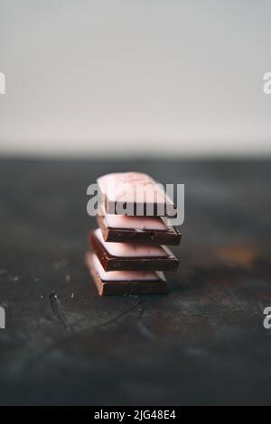 Selektive Konzentration auf vier Schokoladenscheiben auf dunklem Hintergrund. Stockfoto