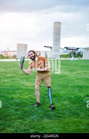 Junger Mann mit Beinprothese, der mit den Teilen der Prothese spielt Stockfoto