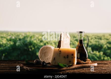 Eine Auswahl an köstlichen sizilianischen Käsesorten und Olivenöl auf einem alten Holztisch aus nächster Nähe Stockfoto