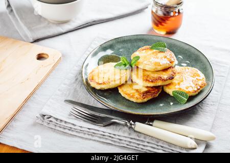 Hüttenkäse-Pfannkuchen mit Honig zum Frühstück. Stockfoto