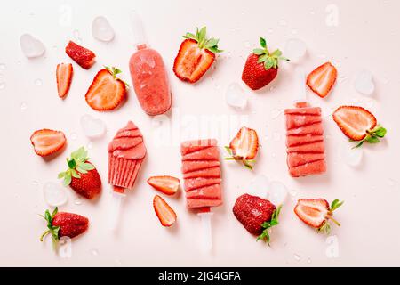 Eiszapfen und frische Erdbeeren auf rosa Hintergrund. Stockfoto