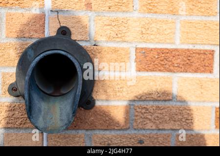 Messing-Metall-Ausguss-Anschluss an der Seite eines Backsteingebäudes Stockfoto