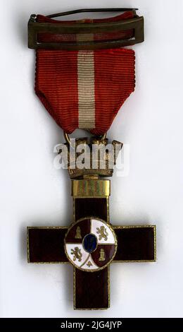 Kreuz des Militärverdienstordens mit rotem Unterscheidungszeichen der Klasse 1. (Joaquín García Morato, Kommandant von Laureado). Griechisches Kreuz in rot emailliert und mit goldenem Rand. Auf einer Vorderseite, zentralem Schild mit goldenem Rand, gegenkruteriert, weiß und rot emailliert und kreuzgeschnitten mit fünf Kasernen: 1. und 4. von Kastilien, 2. und 3. von León und Granada entstammten in Punta. Flordelisado zentrales Excuson mit der Granate in blau emailliert. Auf der Rückseite, Zentralschild emailliert blank, goldener Goldrand, mit den Buchstaben 'mm' goldene Absicht. Im Oberarm, glatte goldene Nadel für die Registrierung. Das Kreuz i Stockfoto