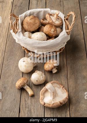 Shitake, portobello und paris Pilze in einem Korb über einem Holztisch. Stockfoto