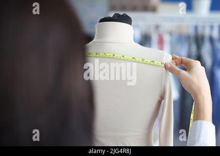 Modedesignerin Stylistin nimmt Messungen mit Zentimeter von Kleidung auf Schaufensterpuppe Stockfoto