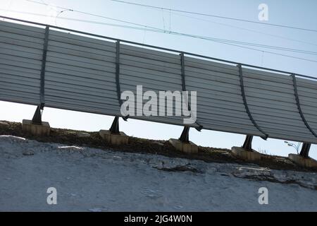 Zaun durch die Eisenbahn. Straßenzaun. Schallisolierte Wand an der Eisenbahn. Stockfoto