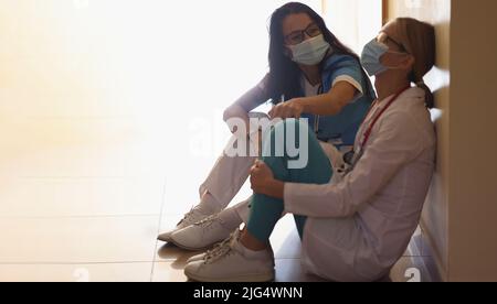 Der Chirurg im Krankenhausflur mit kommuniziert mit dem Arzt, der auf dem Boden sitzt Stockfoto