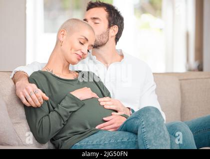 Wieder verliebt. Eine kurze Aufnahme eines anhänglichen jungen, erwartungsvollen Paares, das zu Hause auf dem Sofa sitzt. Stockfoto