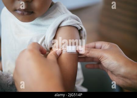 Wieder wie neu. Kurzer Schuss einer Frau, die einen Gips auf den Arm ihrer Kinder legt. Stockfoto