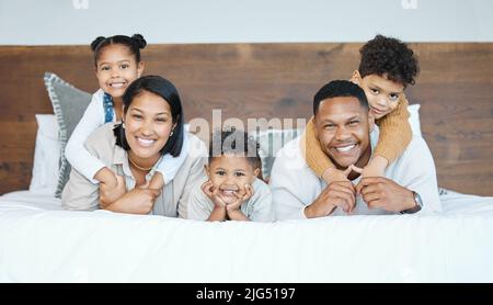 Der Mann unseres Hauses ist ziemlich klein. Porträt einer schönen jungen Familie, die im Bett miteinander redet und sich verbindet. Stockfoto