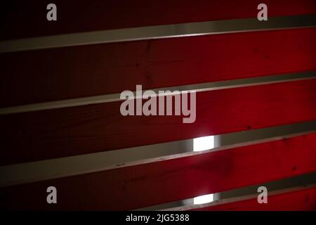 Bretter in rotem Licht. Baum in Neonlicht. Bretter liegen in Reihe. Stockfoto