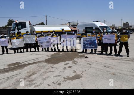 Sarmada, Idlib, Syrien, 7. Juli 2022 ، in der Nähe der Stadt Sarmada im von Rebellen gehaltenen Teil der nordwestlichen Provinz Idlib in Syrien versammeln sich am 7. Juli 2022 humanitäre Helfer, um gegen jede erwartete Schließung des Grenzübergangs Bab al-Hawa mit der Türkei zu demonstrieren und humanitäre Hilfe zu leisten Stockfoto