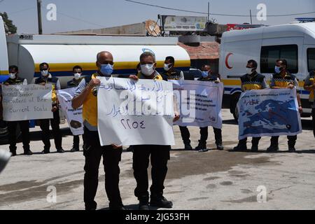 Sarmada, Idlib, Syrien, 7. Juli 2022 ، in der Nähe der Stadt Sarmada im von Rebellen gehaltenen Teil der nordwestlichen Provinz Idlib in Syrien versammeln sich am 7. Juli 2022 humanitäre Helfer, um gegen jede erwartete Schließung des Grenzübergangs Bab al-Hawa mit der Türkei zu demonstrieren und humanitäre Hilfe zu leisten Stockfoto