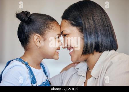 Liebenswert kleines Mädchen und Mutter berühren Stirn. Nahaufnahme von glücklicher Mutter und Tochter, die einander in die Augen schauen. Gemischte Rasse Familie zum Ausdruck bringen Liebe Stockfoto