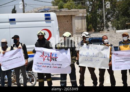 Sarmada, Idlib, Syrien, 7. Juli 2022 ، in der Nähe der Stadt Sarmada im von Rebellen gehaltenen Teil der nordwestlichen Provinz Idlib in Syrien versammeln sich am 7. Juli 2022 humanitäre Helfer, um gegen jede erwartete Schließung des Grenzübergangs Bab al-Hawa mit der Türkei zu demonstrieren und humanitäre Hilfe zu leisten Stockfoto