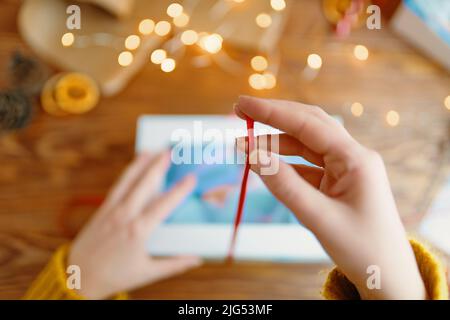 Mädchen Hände in gestricktem Pullover Krawatte Band Schleife auf Geschenkbox. Stockfoto