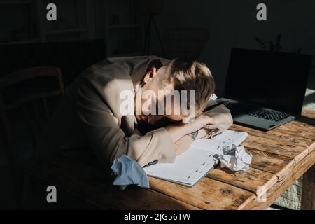 Burnout, emotionale Probleme, Depression Konzept. Traurige müde depressive Frau, die auf dem Tisch zwischen Zeitungen liegt Stockfoto