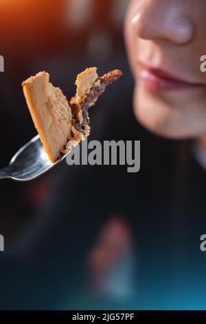 Nahaufnahme des Weibchens, das den Löffel in der Hand hält und im Café Schokoladennusskuchen isst Stockfoto