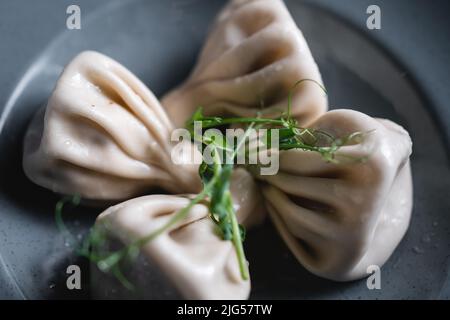 Khinkali- oder georgische Knödel mit Fleisch auf dunklem Teller auf grauem Hintergrund Stockfoto