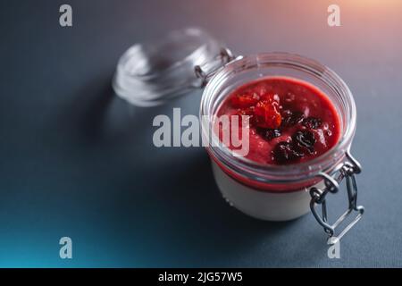 beere Panna Cotta Dessert mit Kirschsauce im Glas auf schwarzem Hintergrund Stockfoto