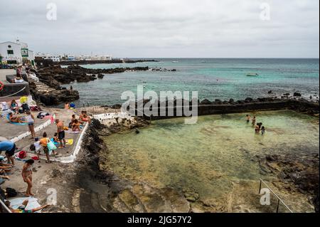 Lanzarote, Spanien. 07.. Juli 2022. An einem Sommertag sonnen sich die Menschen in den natürlichen Pools von Punta Mujeres und kühlen sich ab. Punta Mujeres ist ein kleines Dorf im Nordosten der Vulkaninsel Lanzarote. Quelle: Marcos del Mazo/Alamy Live News Stockfoto