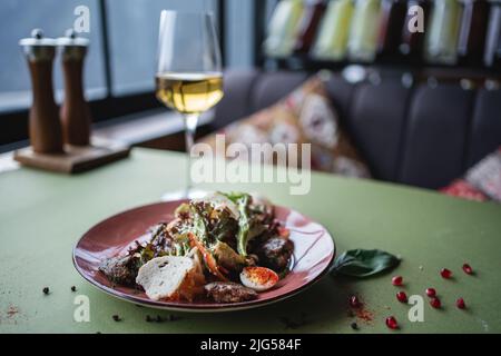 Salat mit Hühnerleber, Ei und Crouton oder Wein im Glas auf dem Restauranttisch Stockfoto