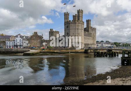 Caernarfon Castle Eagle Tower, Stadtmauer und Anglesey Arms Pub mit Blick über den Fluss Seiont bei Ebbe und gekräuselten Reflexen im Wasser. Stockfoto