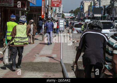 Nakuru, Kenia. 7.. Juli 2022. Arbeiter werden dabei gesehen, wie sie sich darauf vorbereiten, eine solarbetriebene Straßenleuchte auf der Kenyatta Avenue im zentralen Geschäftsviertel zu installieren. Die Regierung von Nakuru County mit Unterstützung der Weltbank installiert Solar-Straßenlaternen, um die Sicherheit der Stadt zu verbessern. Die solare Straßenbeleuchtung ist umweltfreundlich, sie nutzt erneuerbare Energie aus der Sonne und trägt daher nur wenig CO2-Emissionen bei, die für den Klimawandel verantwortlich sind. (Bild: © James Wakibia/SOPA Images via ZUMA Press Wire) Stockfoto