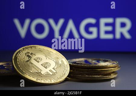Gefallener Stapel Bitcoin-Token und verschwommenes Firmenlogo von Voyager Digital Ltd auf verschwommenem Hintergrund. Konzept für Insolvenz. Stafford, Großbritannien Stockfoto