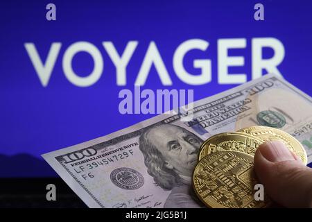 100 Krypto-Token in US-Dollar vor dem Bild und verschwommenes Firmenlogo von Voyager Digital Ltd auf verschwommenem Hintergrund. Konzept. Stafford, Großbritannien, Juli Stockfoto
