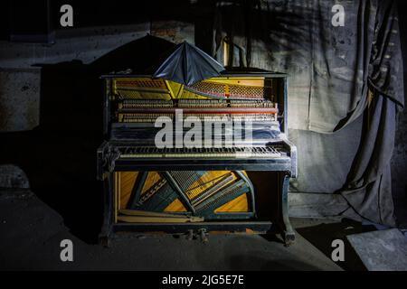 Altes kaputtes Klavier im dunklen Zimmer Stockfoto