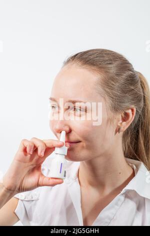 Das Mädchen tropft Nasentropfen aus einer laufenden Nase mit Influenza Stockfoto