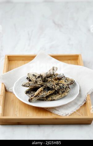 Verkauf Pisang, Indonesischer traditioneller Snack aus geschnittener Banane, in der Sonne getrocknet, tiefgebratene mit Mehlteig Beschichtung. Auf Weißem Tisch Stockfoto