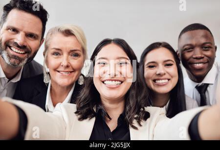 Ein Selfie am Tag hält die Traurigkeit fern. Aufnahme einer Gruppe von Geschäftsleuten, die ein Selfie bei der Arbeit machen. Stockfoto
