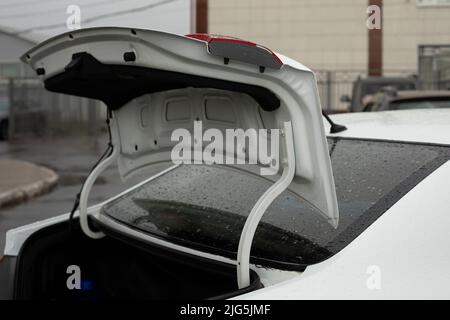Öffnen Sie den Kofferraum des Fahrzeugs. Kofferraum im weißen Auto. Transport auf dem Parkplatz. Stockfoto